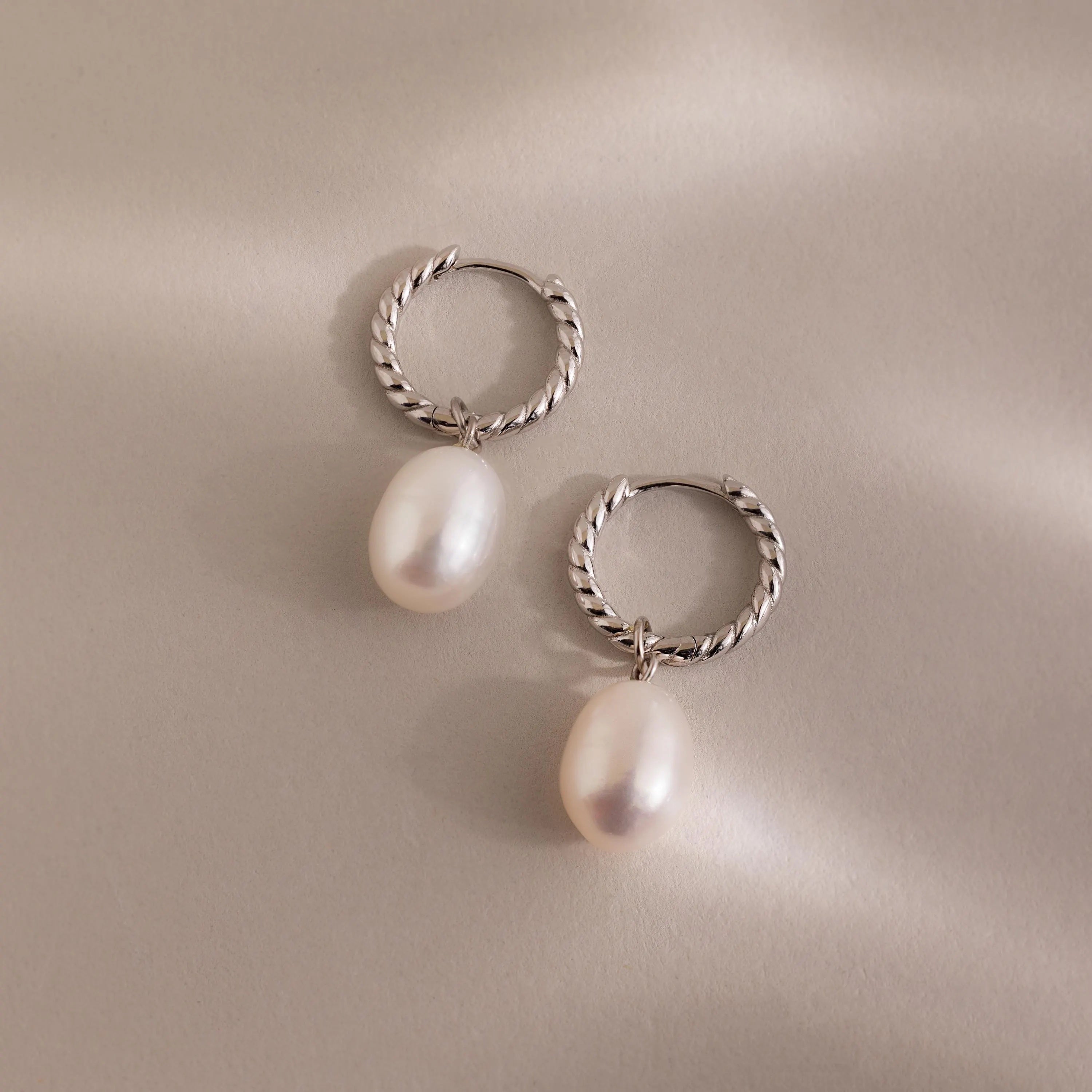 Pair of silver twisted hoop earrings with white freshwater pearls.