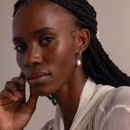 Front-facing portrait of a woman wearing the Twisted Pearl Hoop Earring in silver