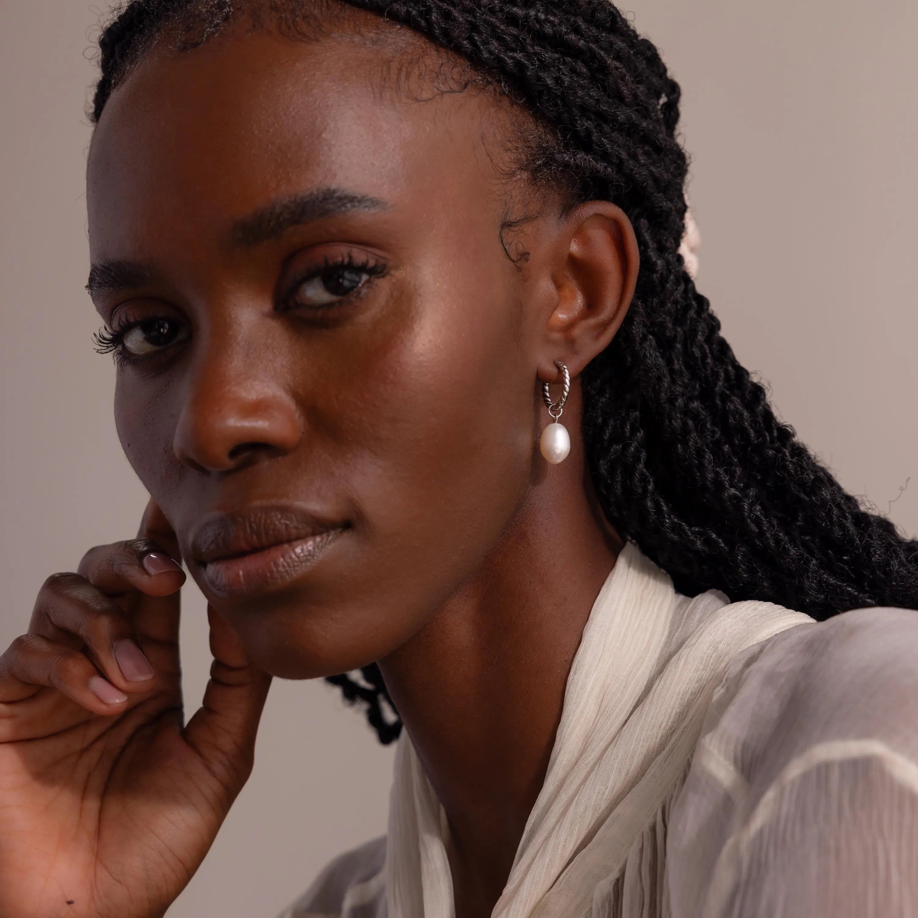 Front-facing portrait of a woman wearing the Twisted Pearl Hoop Earring in silver