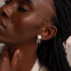 Close-up side view of a woman wearing a white rose and silver bow earring.