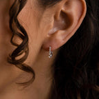 Close-up of an ear adorned with Lace Diamond Huggies—elegant, delicate silver earrings featuring small gemstones—perfect for adding a touch of sophistication.