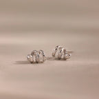 Silver 3D twisted snake stud earrings resting on a neutral surface.