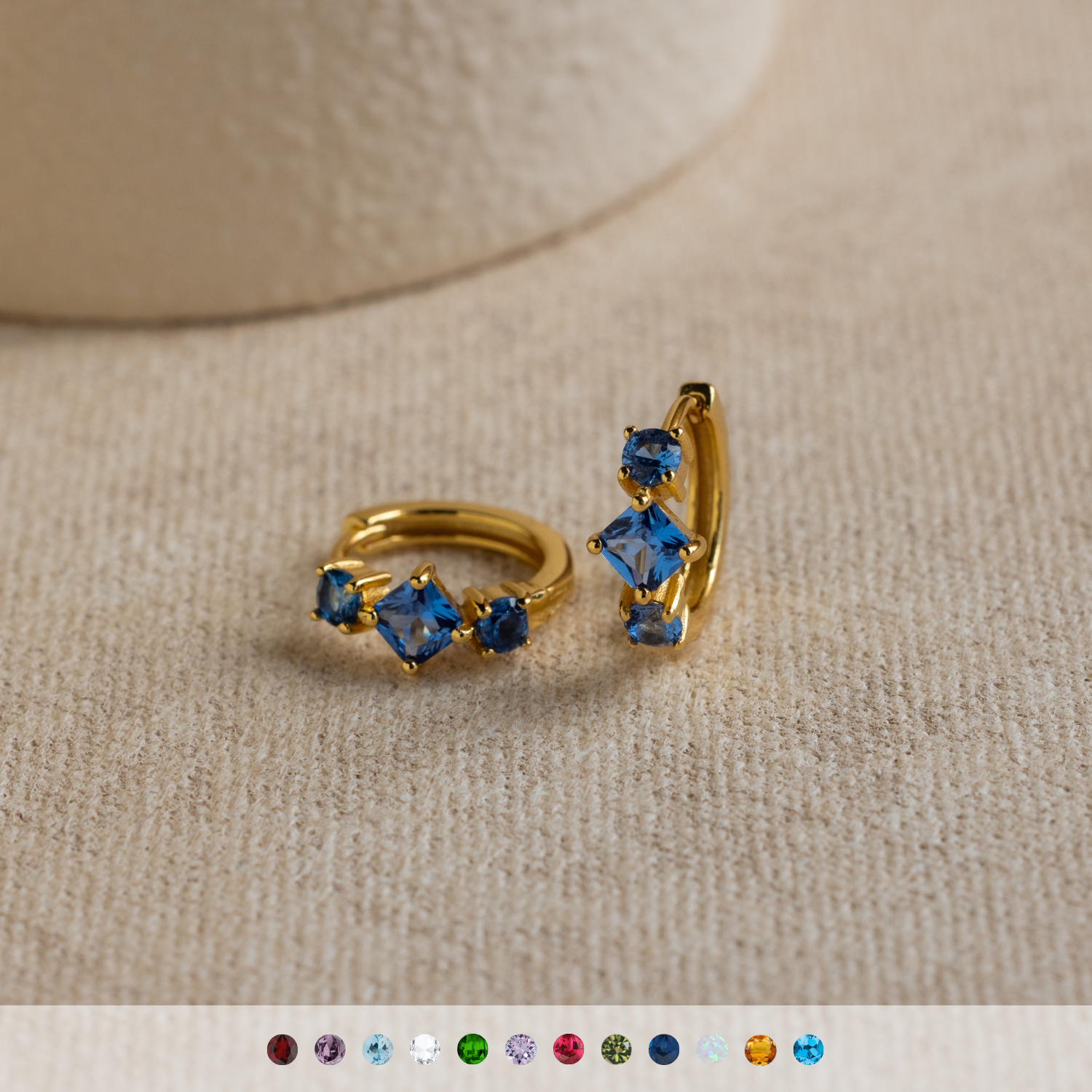 A computer screen displays a stylish selection of gemstone earrings, featuring the elegant Princess Cut Birthstone Huggies.