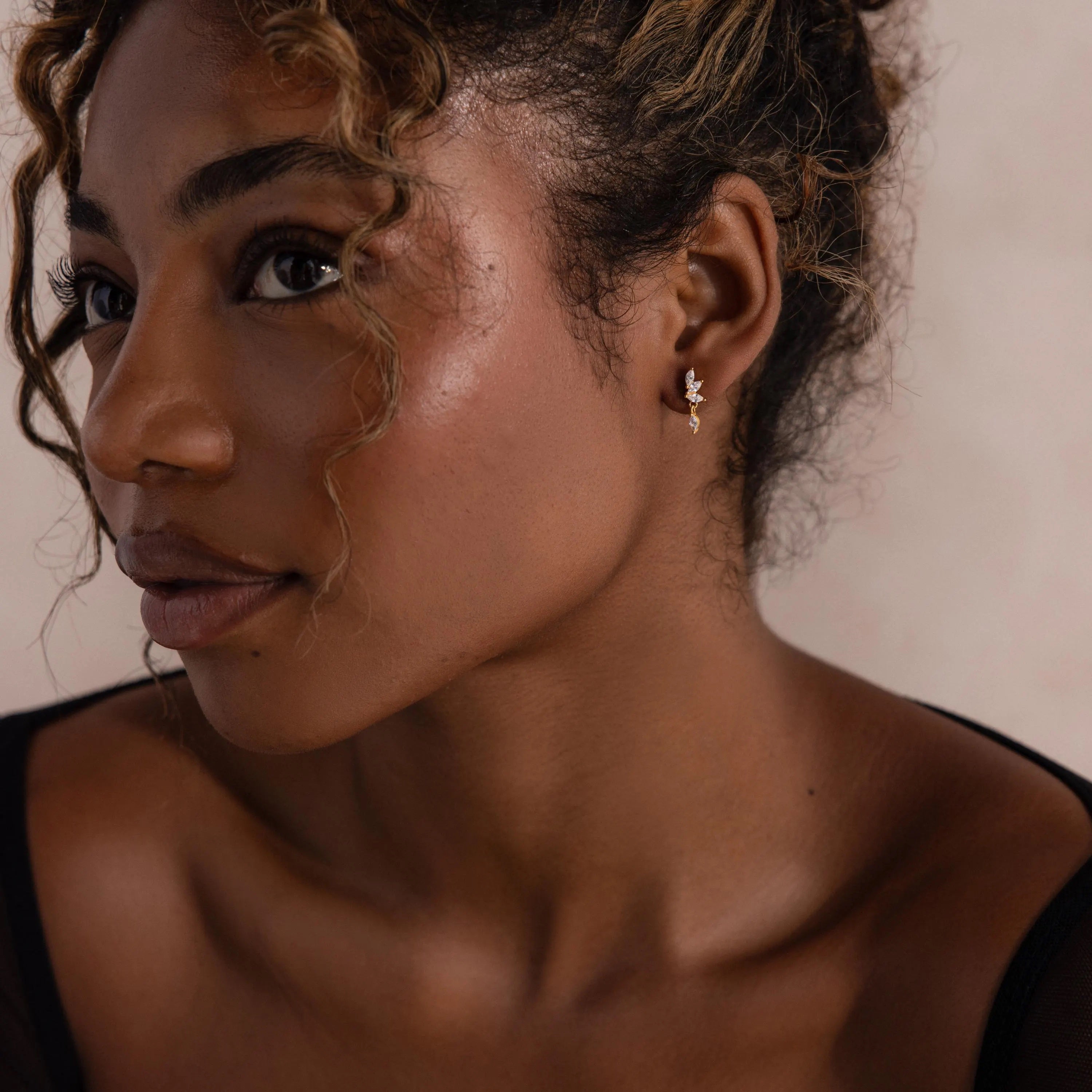 Model wearing gold CZ diamond drop earrings with four marquise-cut stones.