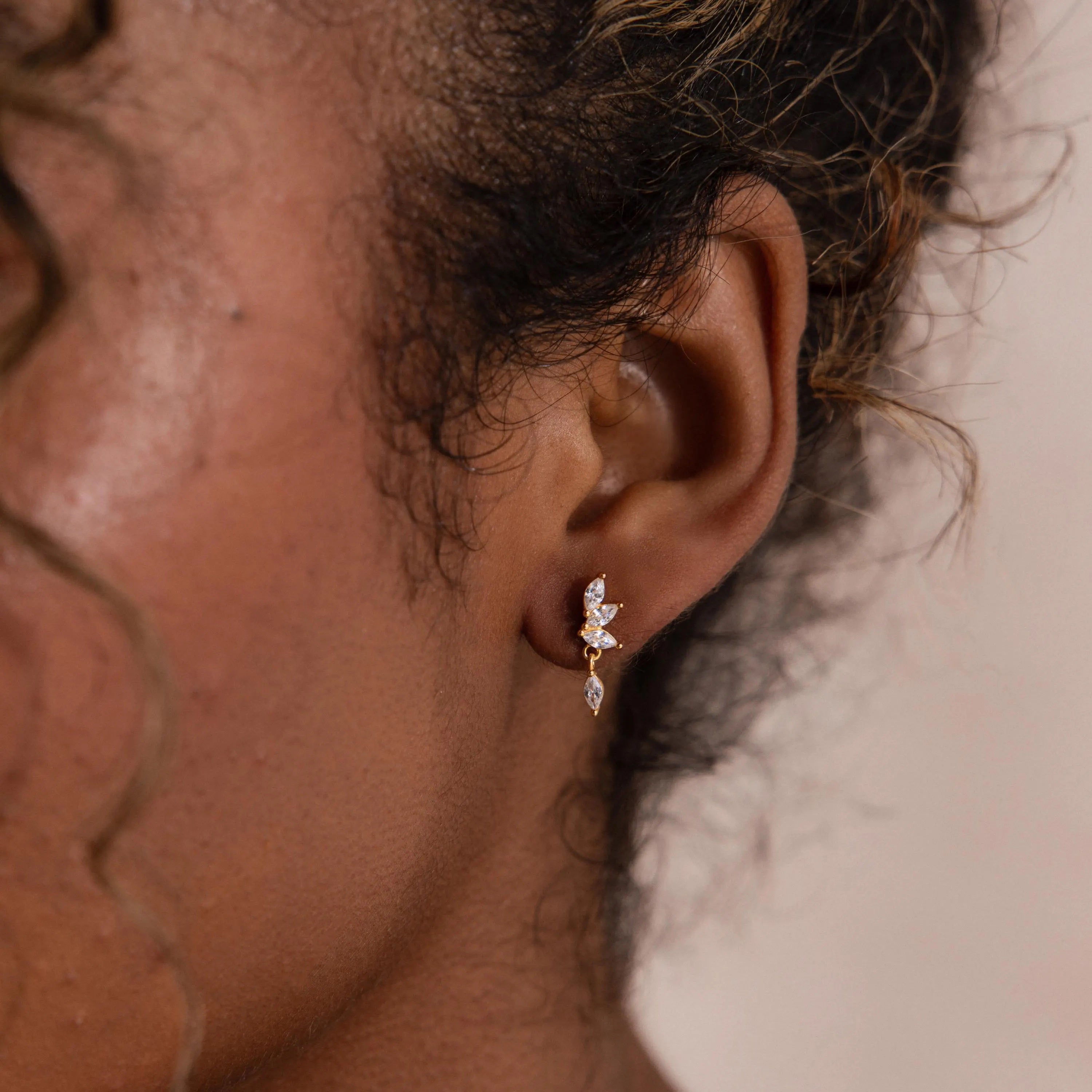 Model wearing dainty gold CZ diamond drop earrings with four marquise-cut stones.