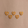 5 gold Ribbed Heart Initial Stud Earrings with the letters A, B, C, D, and E in pave detailing, displayed on a neutral background.