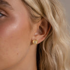 Model wearing a gold Ribbed Heart Initial Stud Earring with the letter R in CZ pave detailing.