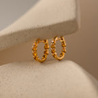 Mini Topaz Beaded Huggies shown on a soft beige curved background—ideal for those who appreciate modern huggie earrings with timeless elegance.