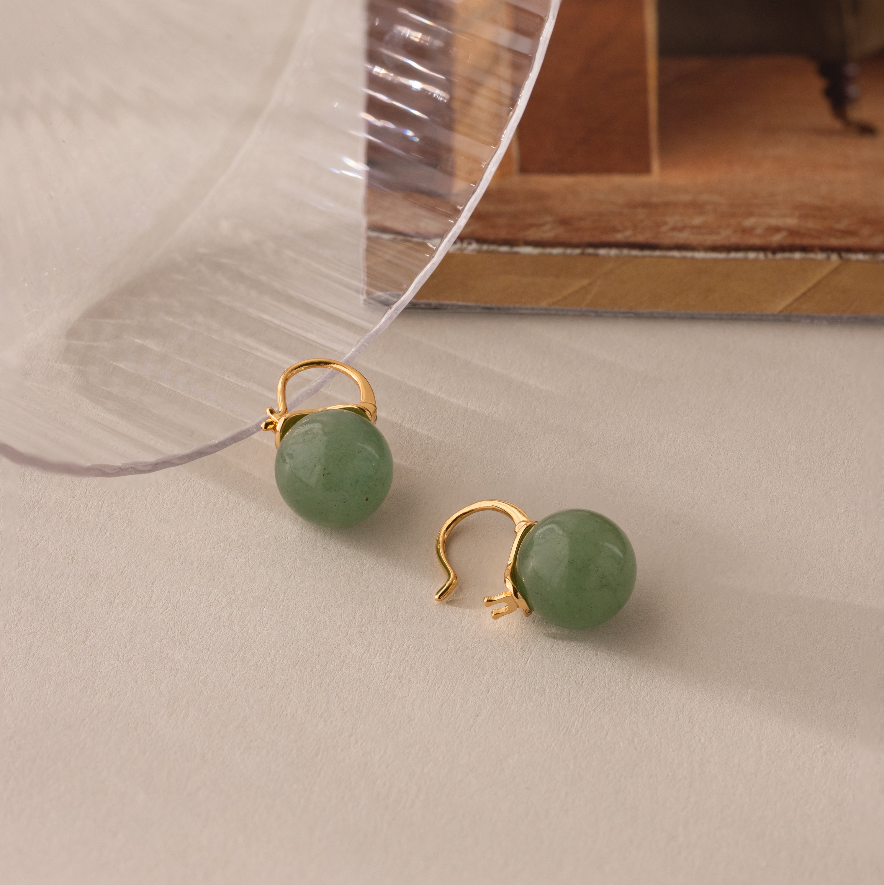 Close-up of gold Jade Dome Drop Earrings featuring rounded green gemstones on dainty hoops.