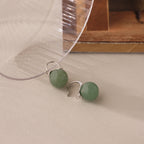 Close-up of silver Jade Dome Drop Earrings featuring rounded green gemstones on dainty hoops.