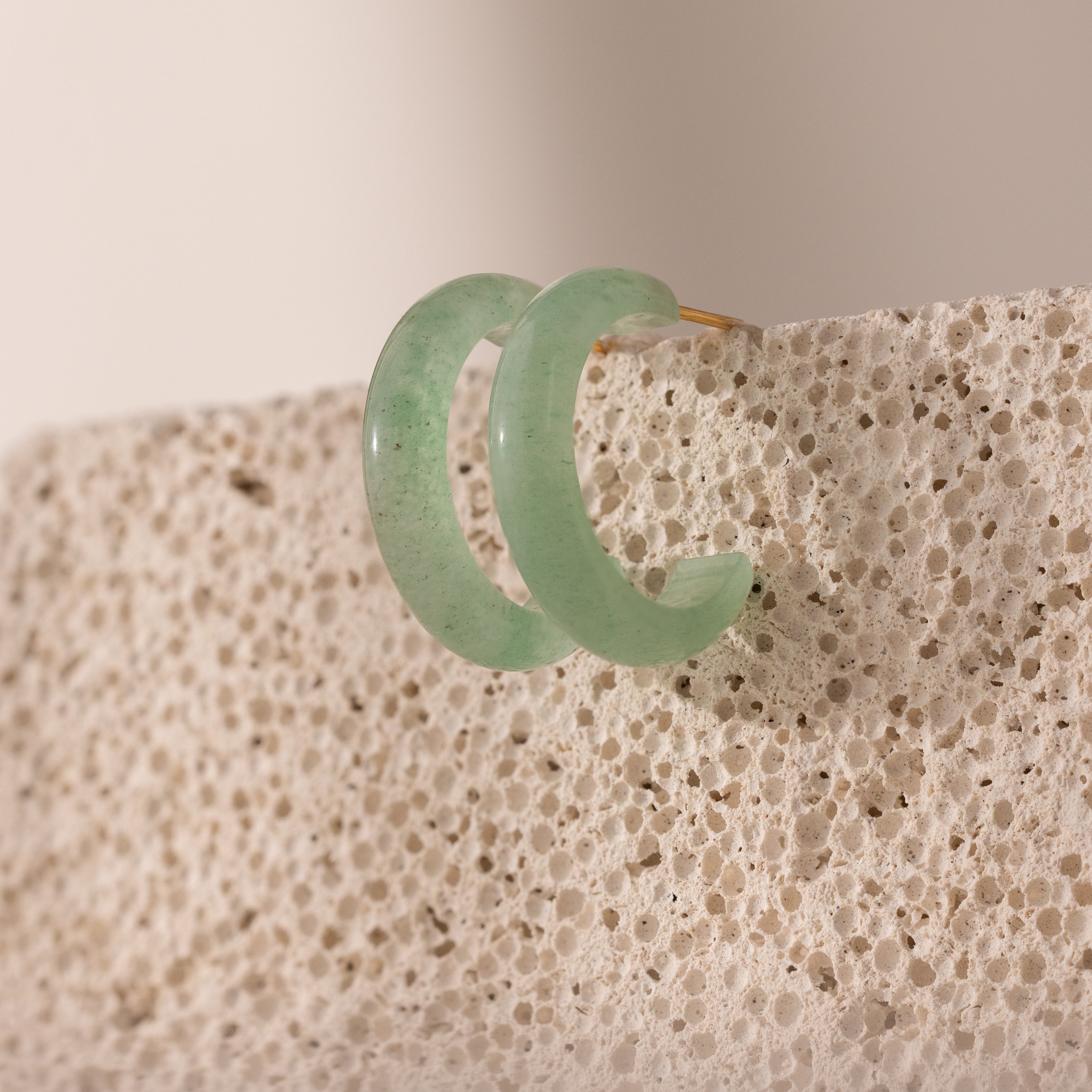 Pair of Jade Hoop Earrings, featuring a chunky hoop design with a soft green natural jade gemstone, displayed on a natural surface.