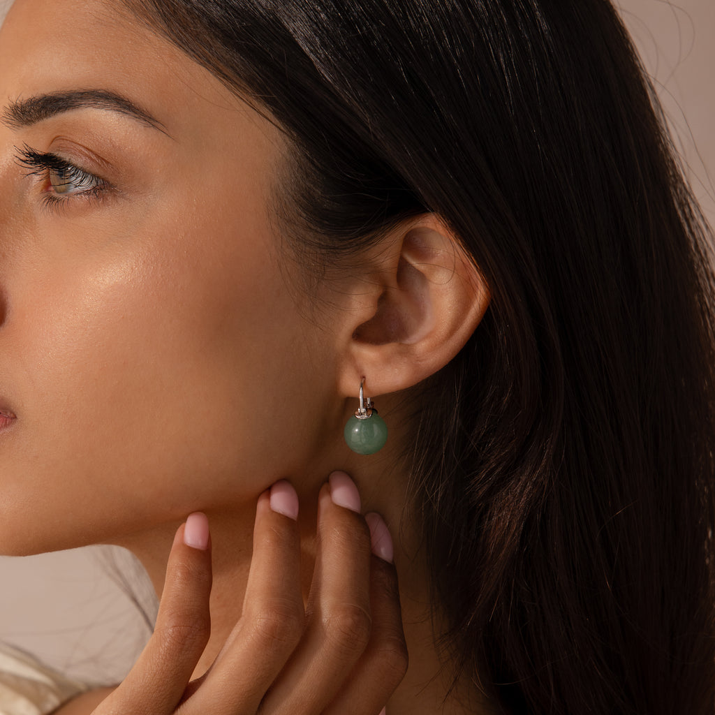 Model wearing silver Jade Dome Drop Earrings featuring rounded green gemstones on dainty hoops.