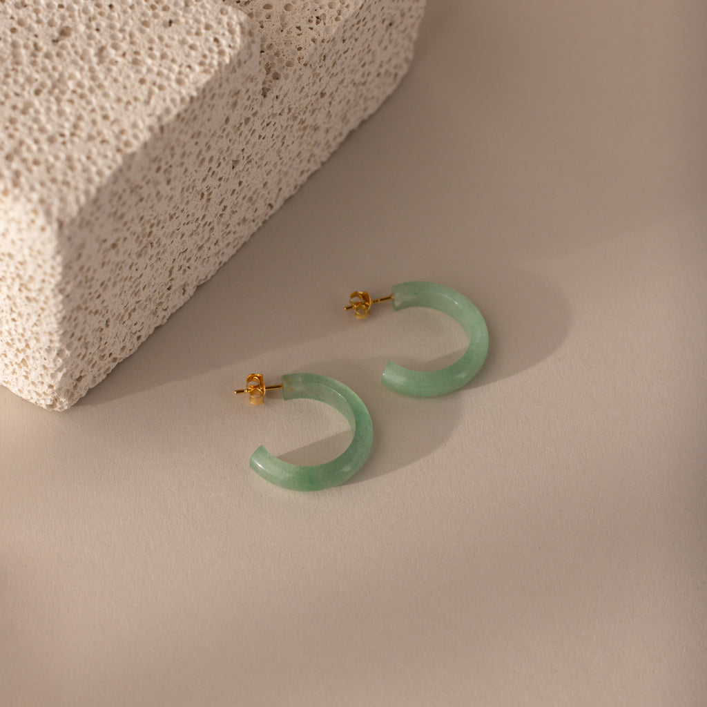 Flat-lay of Jade Hoop Earrings in gold, featuring a chunky hoop design with green jade gemstone on a butterfly back closure.