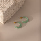Flat-lay of Jade Hoop Earrings in gold, featuring a chunky hoop design with green jade gemstone on a butterfly back closure.