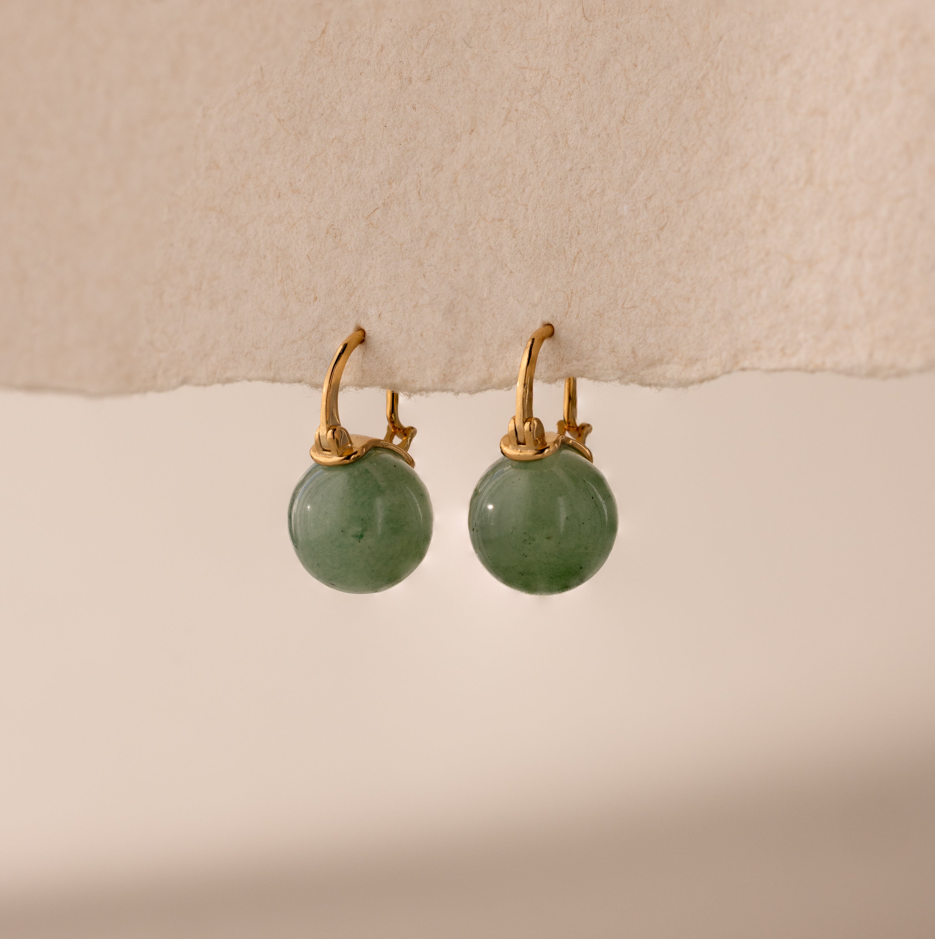 Gold Jade Dome Drop Earrings featuring rounded green gemstones on dainty hoops, displayed on a neutral paper.