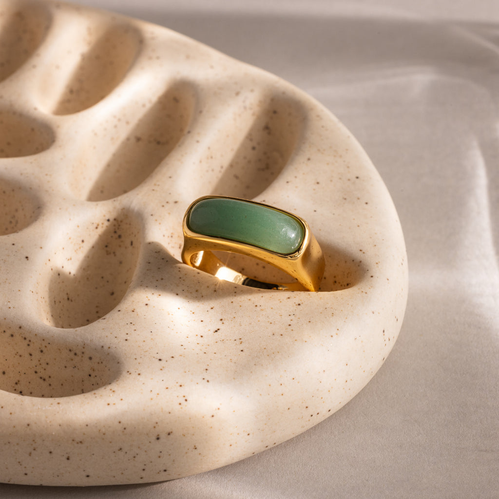 Close-up of a gold signet ring with a polished green jade gemstone inlay.