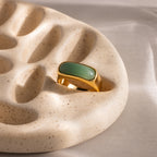 Close-up of a gold signet ring with a polished green jade gemstone inlay.