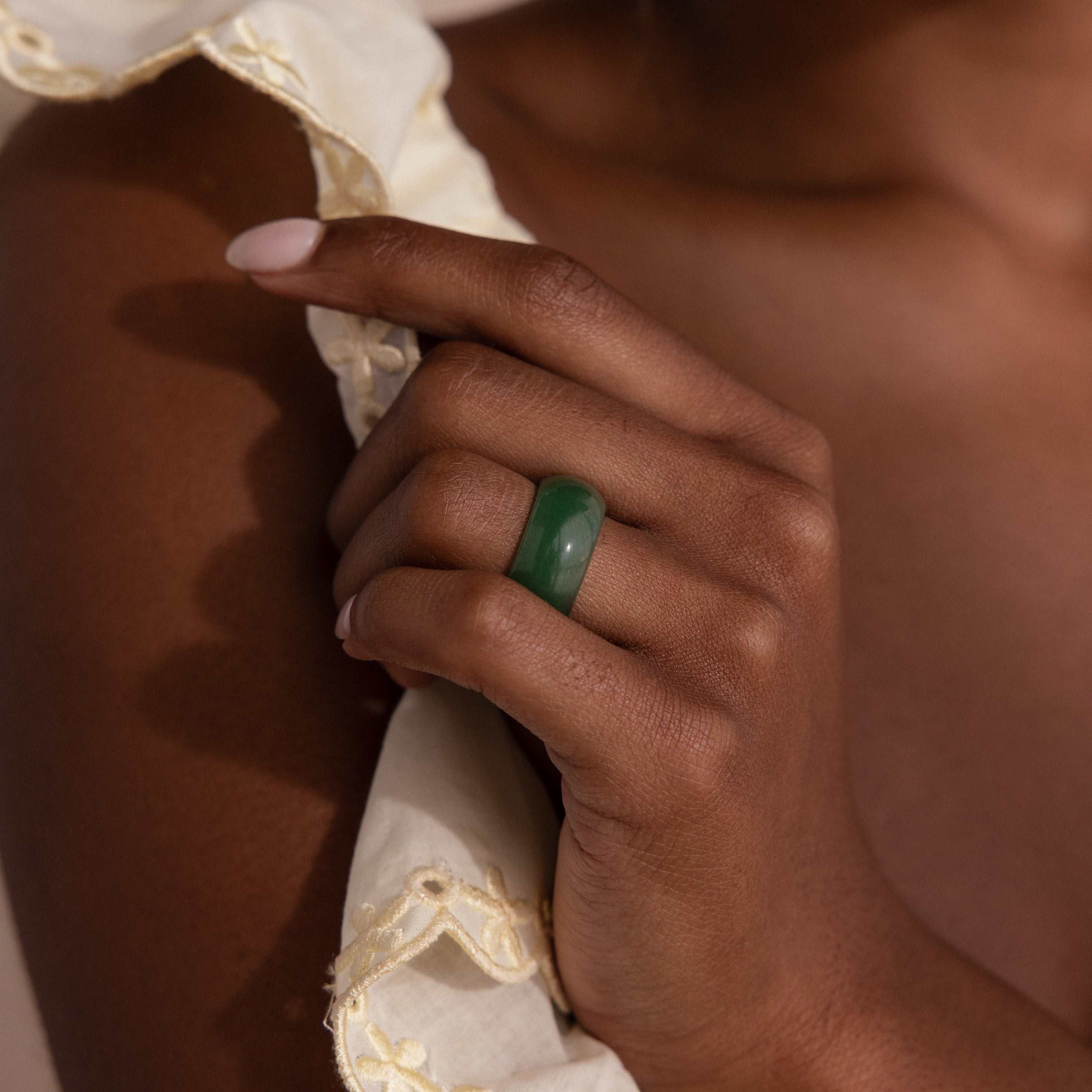 Model wearing a thick green jade gemstone statement ring with a smooth, glossy finish.