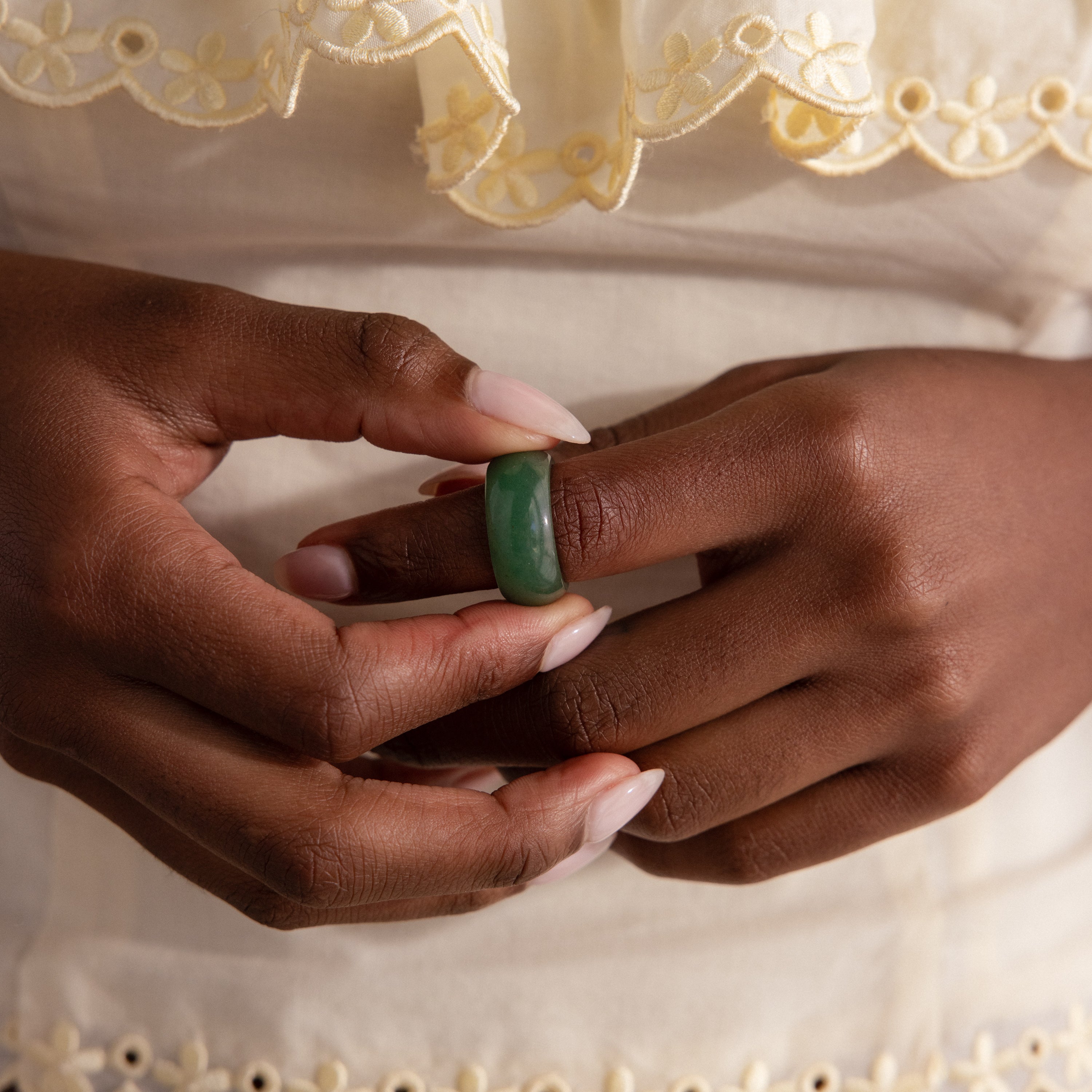 Model wearing a thick green jade gemstone statement ring with a smooth, glossy finish.
