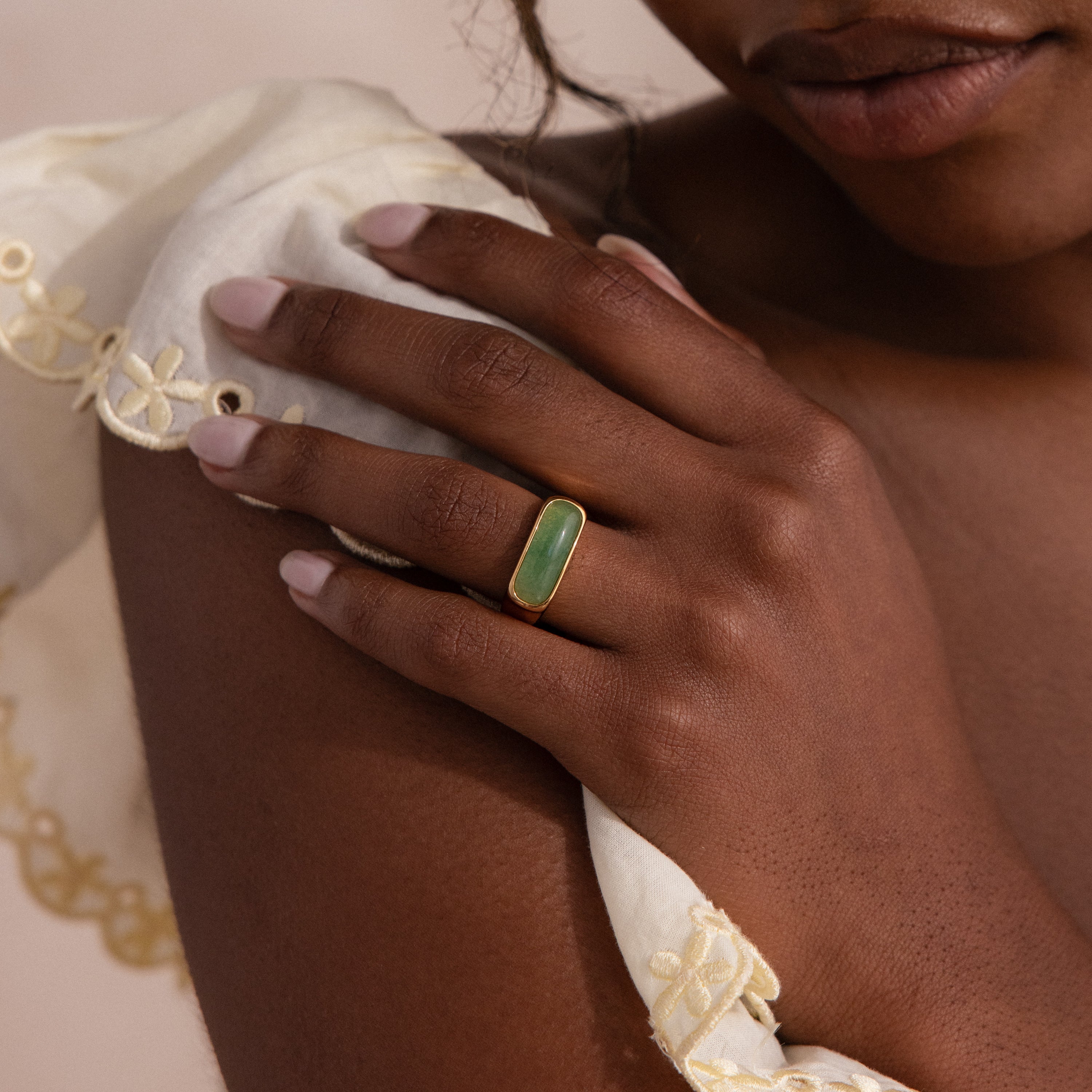 Model wearing a gold signet ring with a polished green jade gemstone inlay.