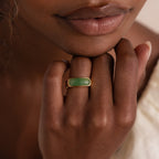 Model wearing a gold signet ring with a polished green jade gemstone inlay.