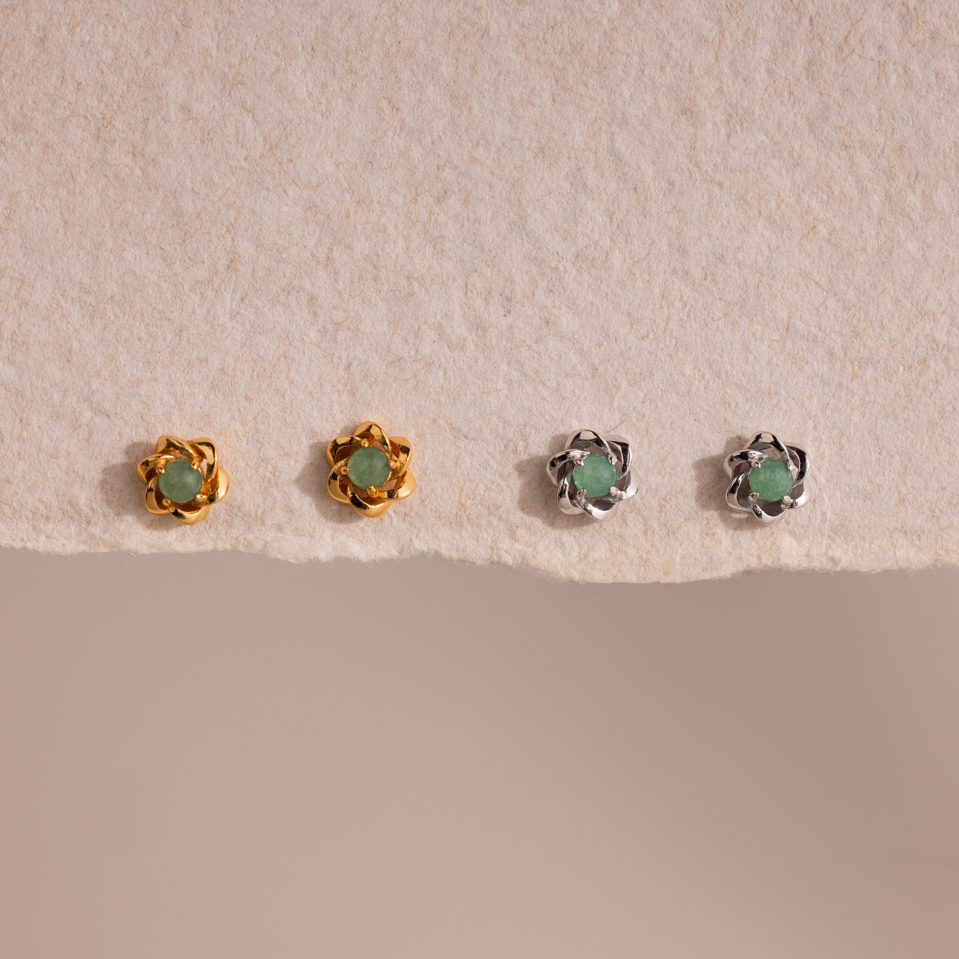 Set of four Mini Jade Flower Studs—two gold, two silver—with green stones, displayed on textured beige paper. These delicate earrings add an elegant touch to any outfit.