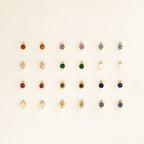 Twenty-five pairs of dainty earrings, including Raindrop Aquamarine Studs, are arranged in a neat grid on a light background.