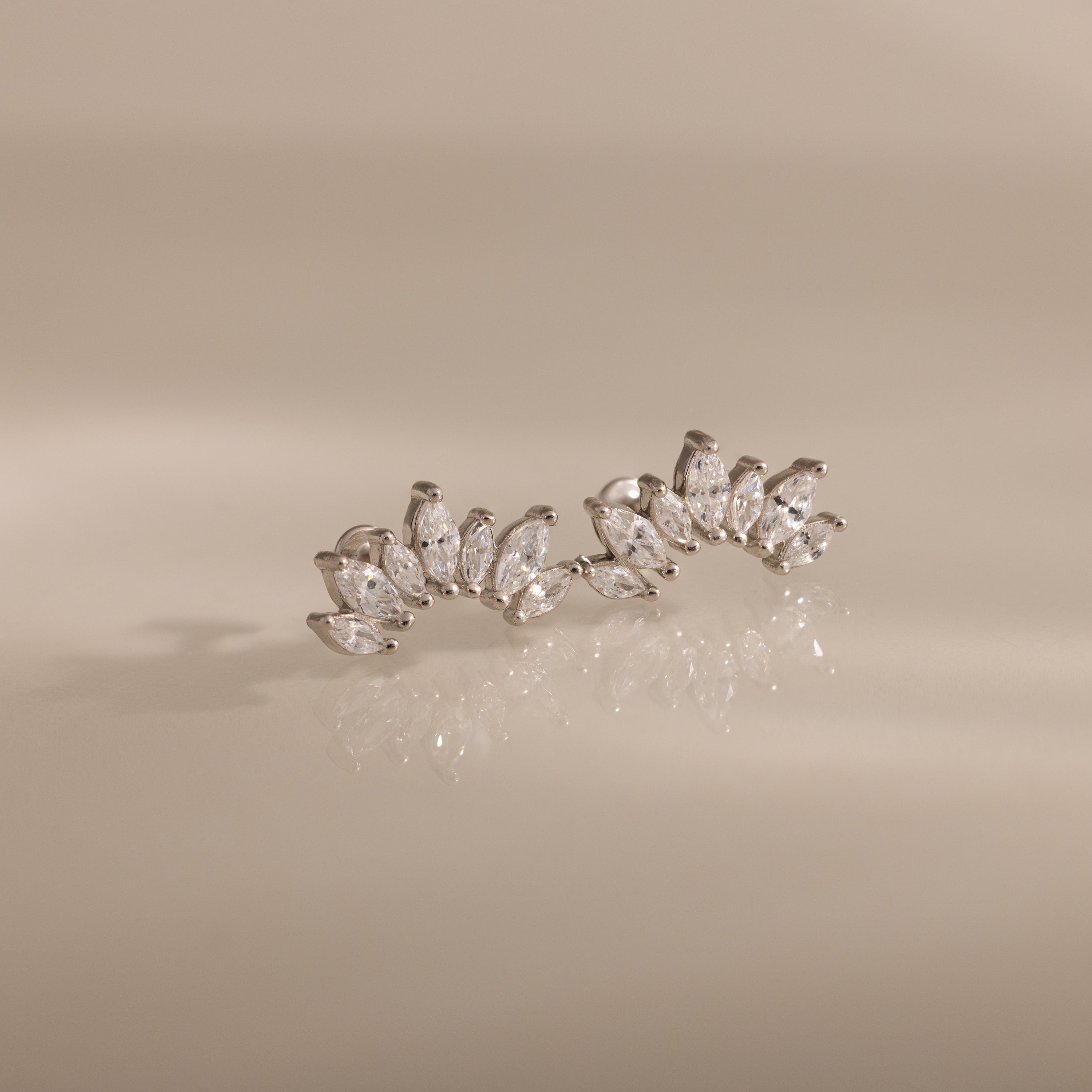 Marquise Diamond Arc Climbers in Silver, featuring marquise stones in a fan pattern, displayed on a beige reflective surface.