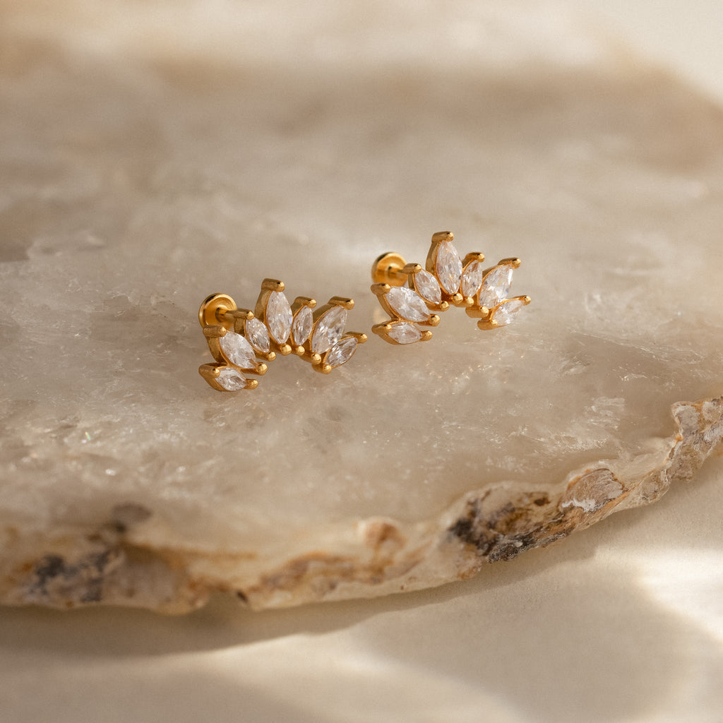 Marquise Diamond Arc Climbers in 18K Gold, featuring marquise-shaped clear stones in a leafy design, displayed on a light stone surface—a stunning update on classic marquise earrings.