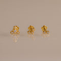 Close up of three gold crystal cluster flat back stud earrings featuring graduated two, three, and four stone designs.
