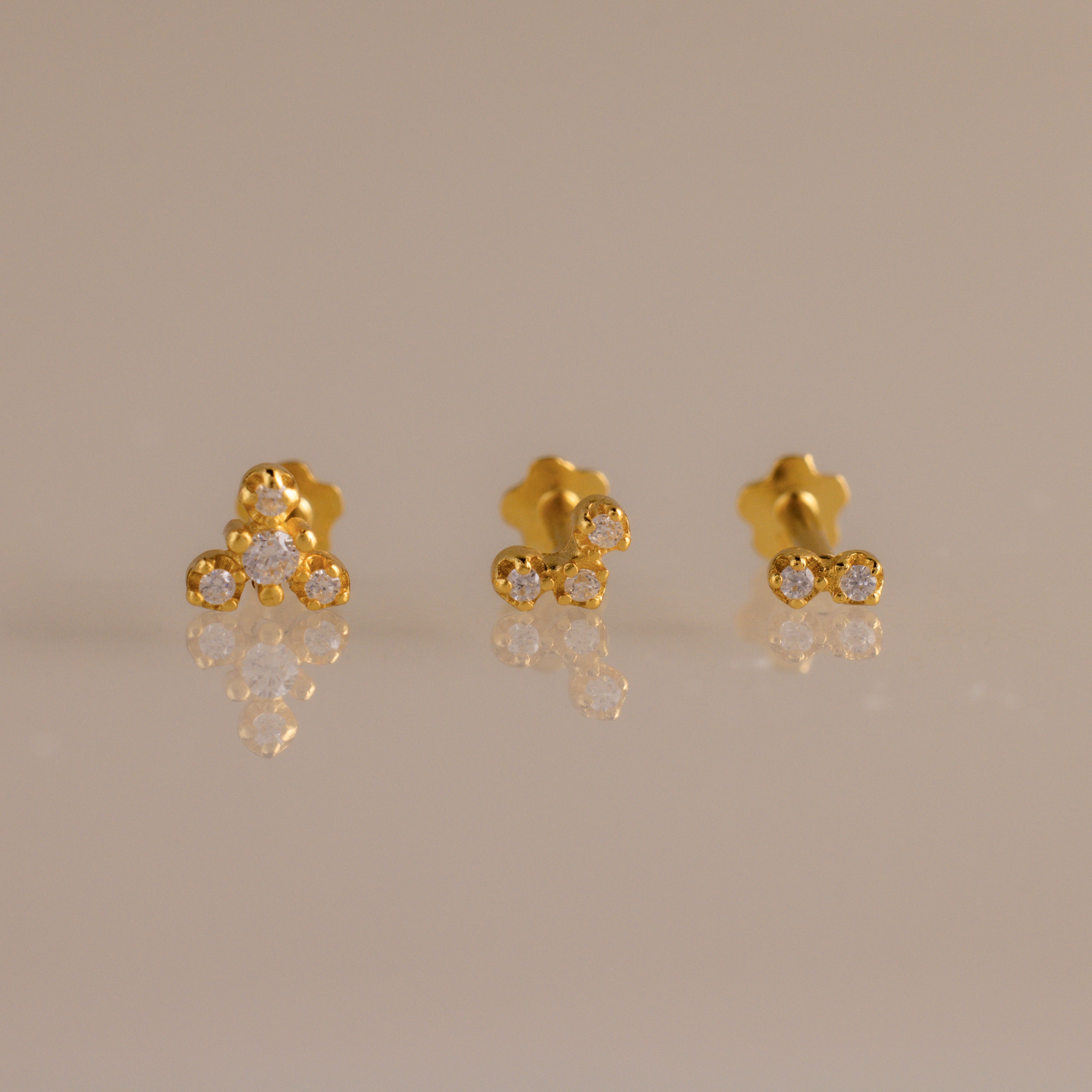 Close up of three gold crystal cluster flat back stud earrings featuring graduated two, three, and four stone designs.