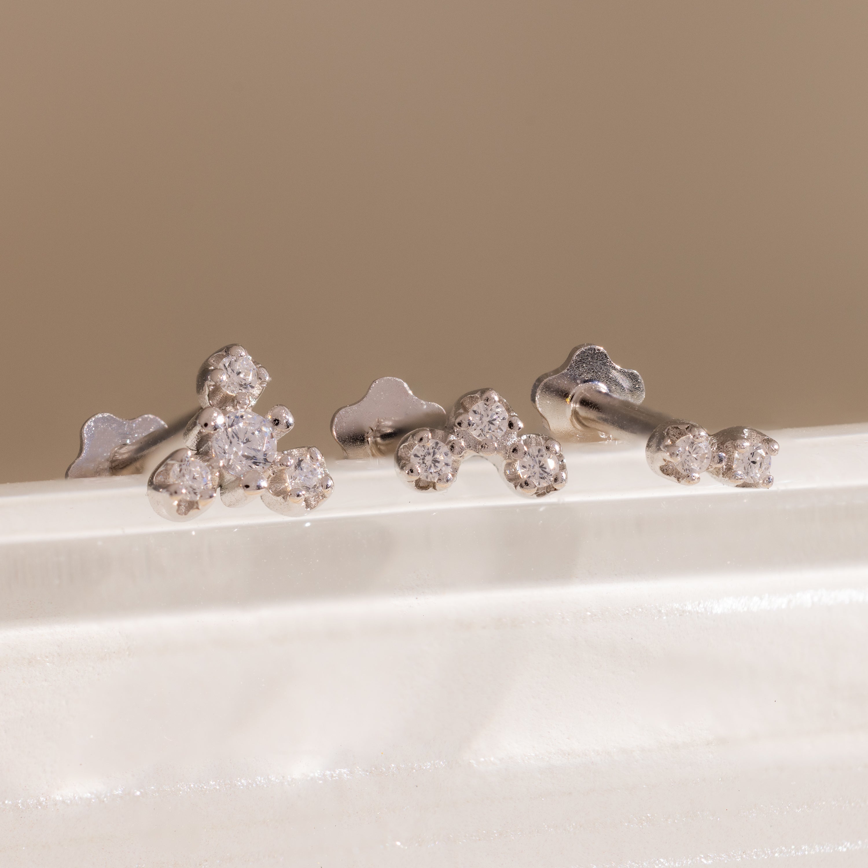 Three silver crystal cluster flat back stud earrings displayed on a white surface, showing graduated two, three, and four stone designs.