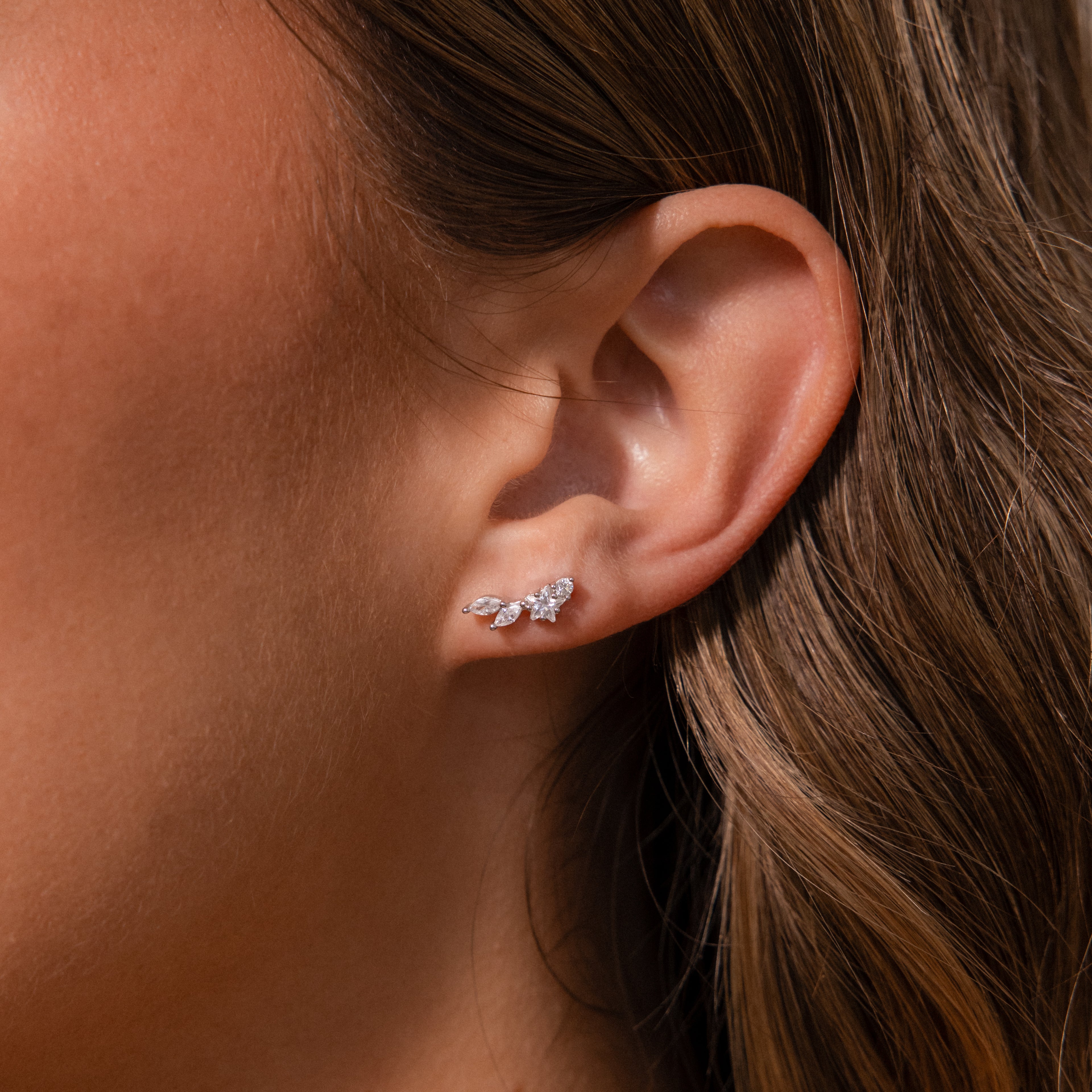 Close-up of a womans ear wearing Diamond Starfall Climbers in Silver, featuring delicate marquise cut gems arranged in a leaf-inspired design.