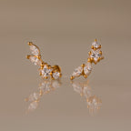Diamond Starfall Climbers in 18K Gold, featuring marquise and round clear gemstones, elegantly displayed on a reflective beige surface.