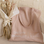 Free Gift of Choice blush pink tote bag with “Caitlyn Minimalist Made with Love” text, shown beside dried flowers—ideal for anyone who loves adorable totes or wants a stylish free gift.