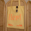 Brighten your day with the Free Gift of Choice—a yellow tote bag featuring "Her!" in orange text and sunglasses detail, making it a perfect pick for tote bag lovers or as a cheerful free gift.