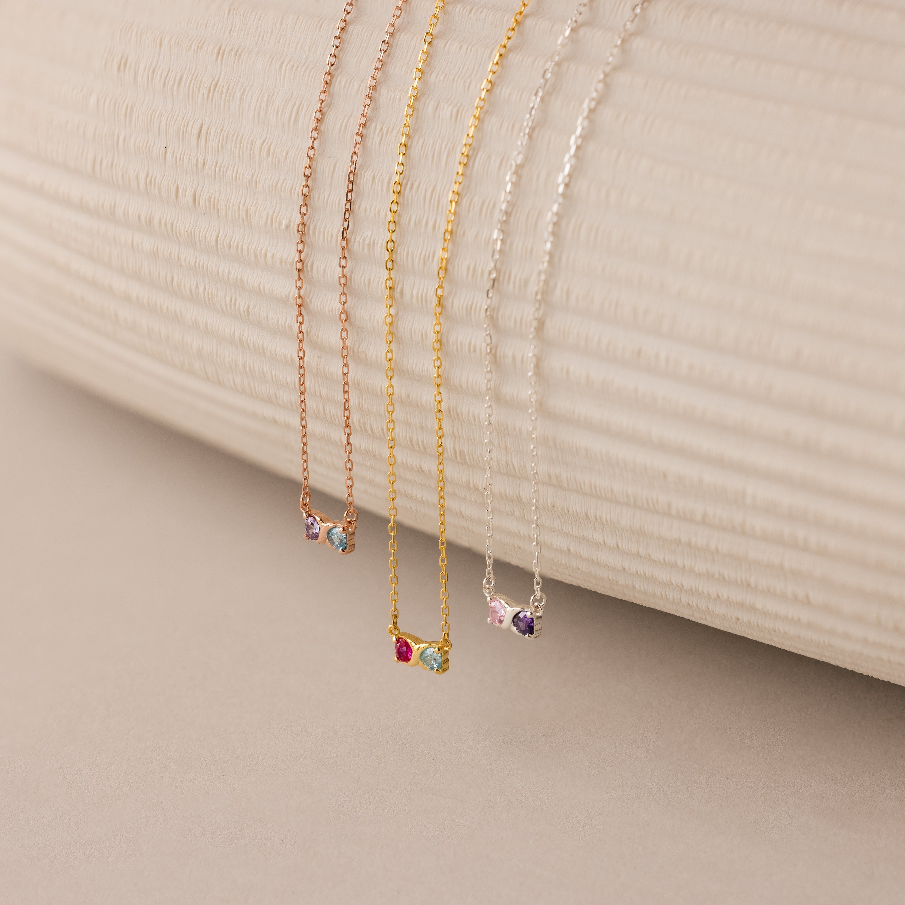 The Toi et Moi Infinity Heart Birthstone Necklace features three delicate chain necklaces in rose gold, gold, and silver with colorful gemstone pendants—ideal for meaningful, personalized jewelry.