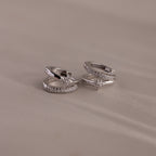 Two sterling silver rings with diamond accents and star motifs are displayed on a soft beige surface—perfect for pairing with the Starburst Pave Duo Huggies in Sterling Silver.