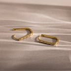 Dainty Pave Link Earrings in 18K Gold with embedded cubic zirconia, displayed on a textured light-colored surface.