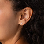 Model wearing dainty silver cross stud earrings.