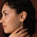 Model wearing dainty silver cross stud earrings.