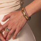 A hand wearing the Mixed Metal Bangle and minimalist jewelry rests on a hip, contrasted against a beige outfit background.