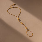 The Moonstone Hand Chain Bracelet in 18K Gold features three oval moonstone accents, shown on a beige background with soft lighting.