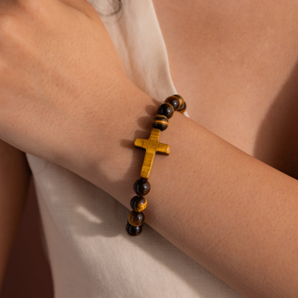 Model wearing the Tigers Eye Cross Bracelet featuring round polished tiger's eye beads and a horizontal tiger's eye cross charm.