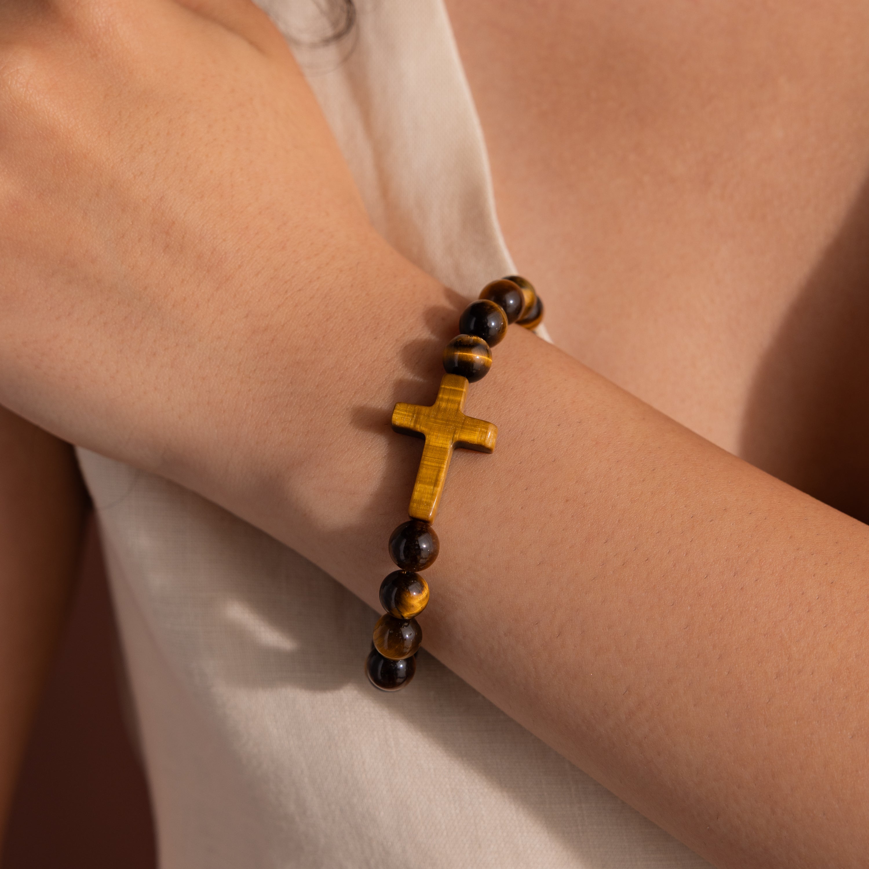 Model wearing the Tigers Eye Cross Bracelet featuring round polished tiger's eye beads and a horizontal tiger's eye cross charm.