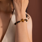 Model wearing the Tigers Eye Cross Bracelet featuring round polished tiger's eye beads and a horizontal tiger's eye cross charm.