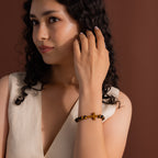 Model wearing the Tigers Eye Cross Bracelet featuring round polished tiger's eye beads and a horizontal tiger's eye cross charm.
