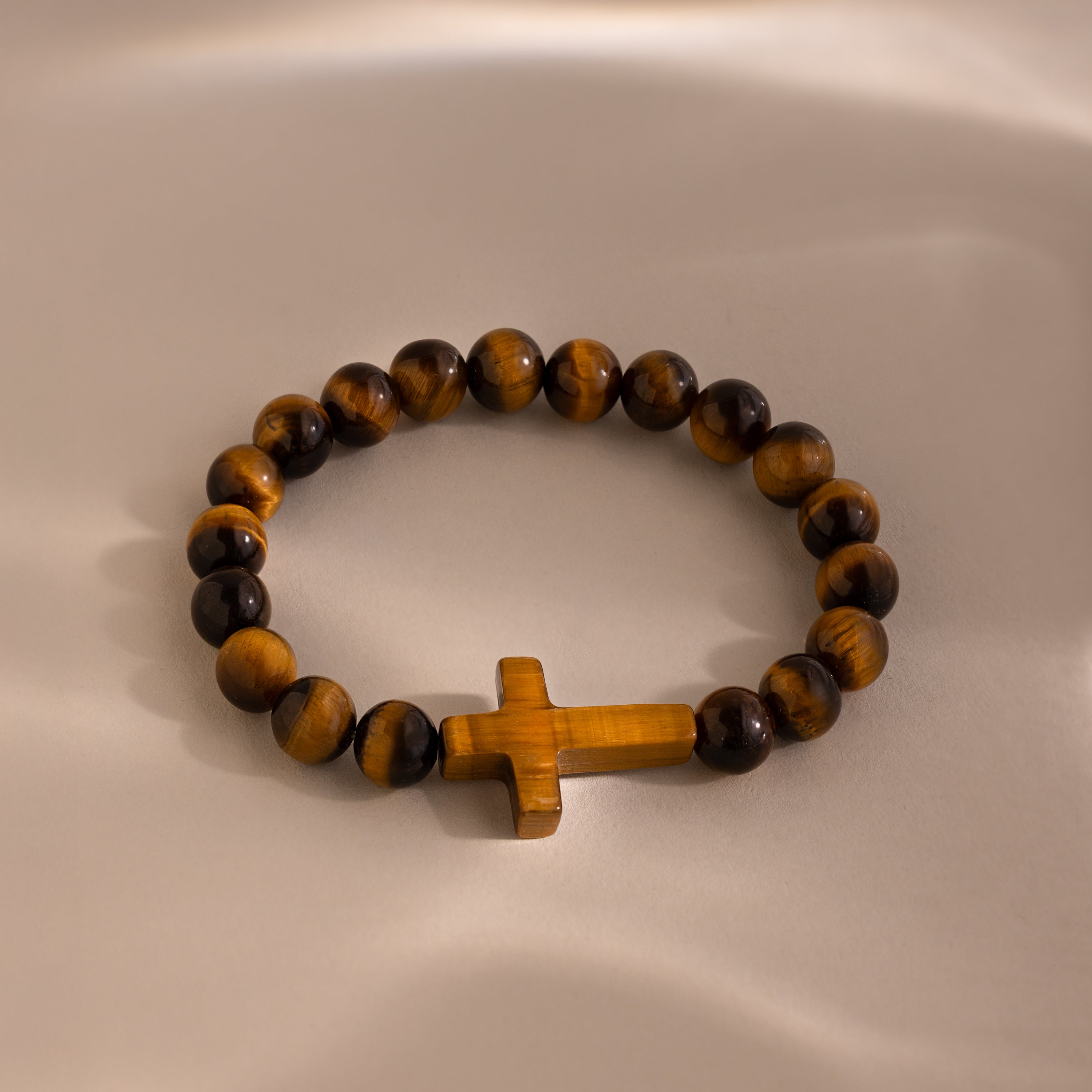 Tigers Eye Cross Bracelet featuring round polished tiger's eye beads and a horizontal tiger's eye cross charm, displayed on a neutral background.