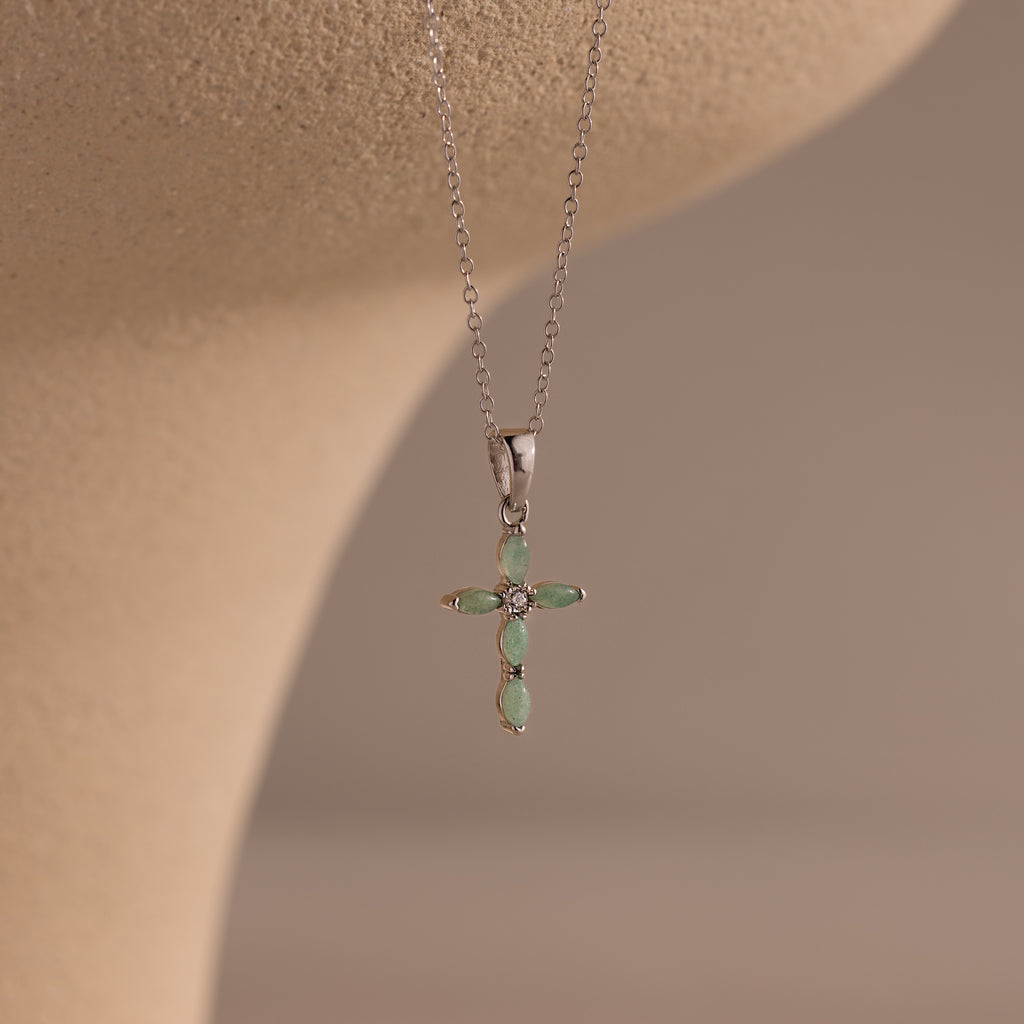 Close-up of a silver necklace with a jade cross pendant, featuring marquise-cut green stones and a CZ diamond center.