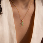 Model wearing a gold jade cross pendant necklaces featuring marquise-cut green stones and a CZ diamond center.